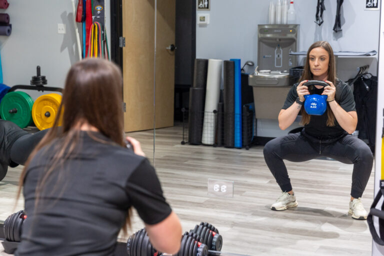 Woman squatting weight at a specialty gym in Chicago.