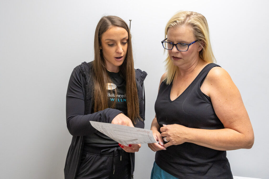 A female physician talks to a female patient, pointing to a document, explaining sore rotator cuff treatment in Bucktown.