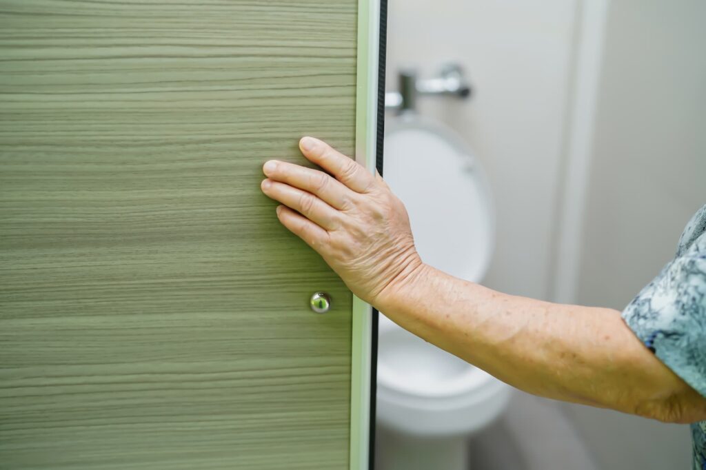 Close up of a senior woman entering a bathroom stall because of her urninary incontinence