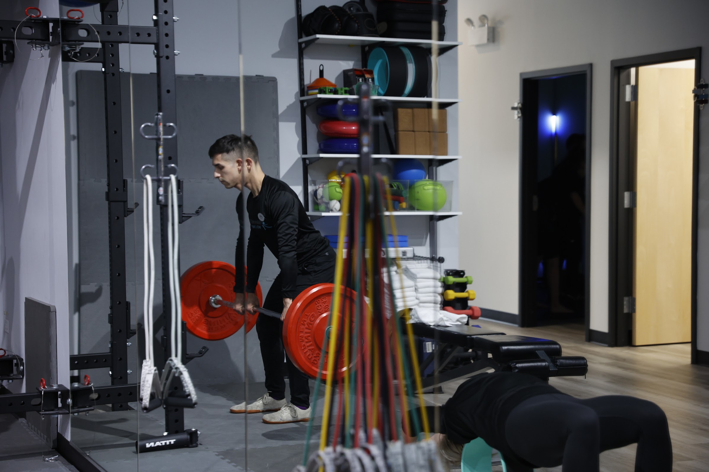 Trainer lifting a barbell during 2XPT strength training at Balanced Flow Wellness in Chicago