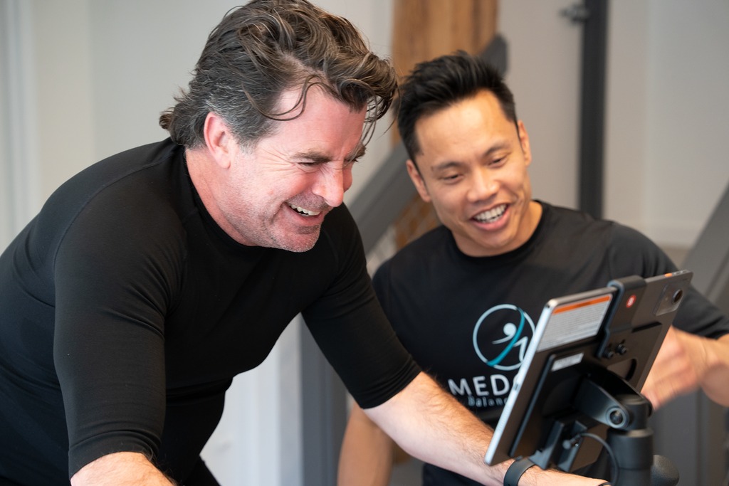 Client riding the CAROL bike with a MedGym coach at the Balanced Flow studio in Chicago