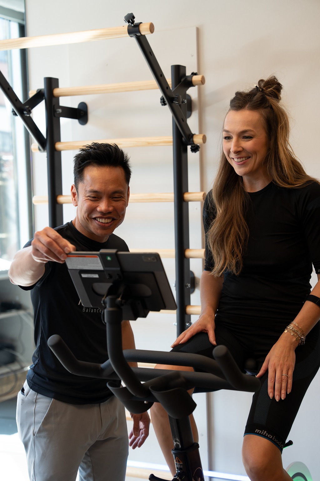 MedGym coach and client smiling beside the CAROL bike