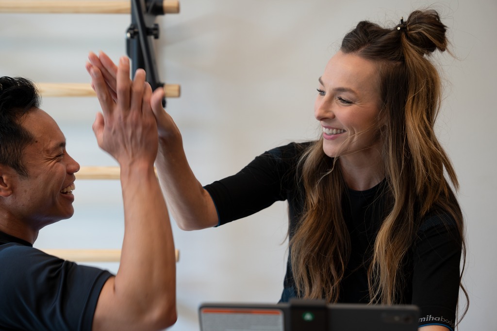 Coach and client high-fiving after a CAROL bike sprint session
