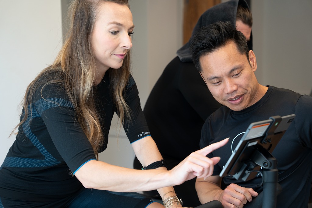Client pointing to her CAROL bike results while her coach explains the metrics