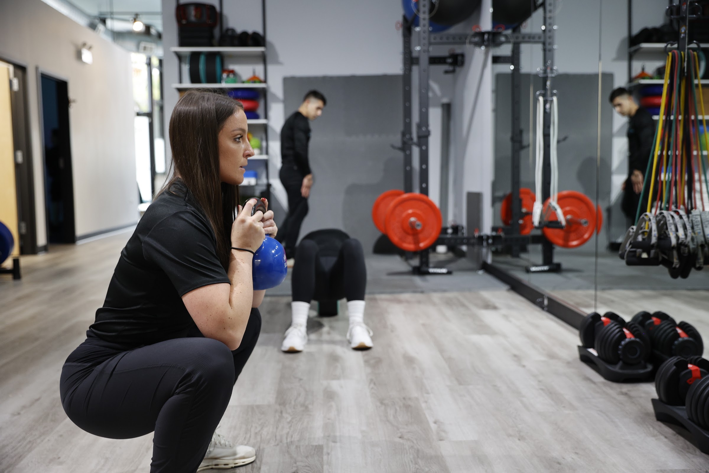 Trainer doing a kettlebell goblet squat during sports physical therapy and strength training in Chicago